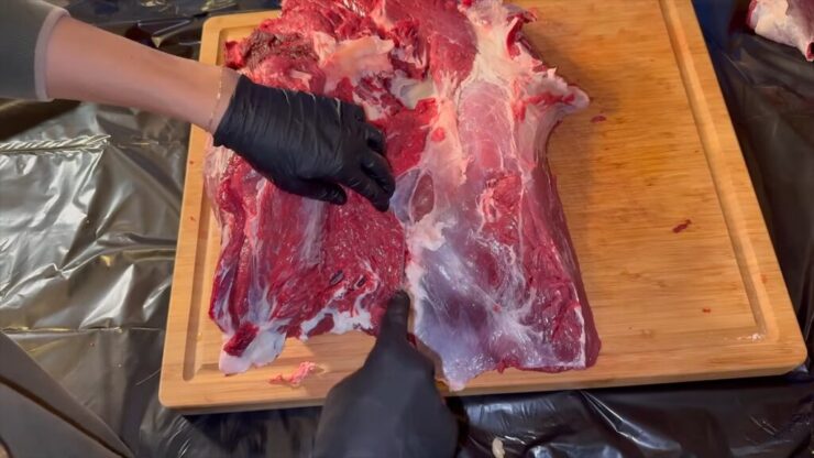 Separated deer hind quarter cuts displayed on a cutting board after removing the bottom round muscle